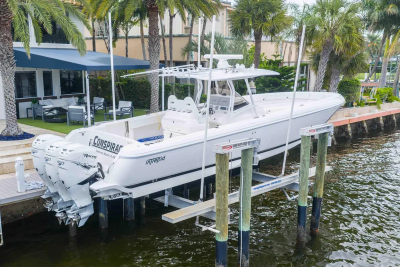 Slide: The Image of 2019 Intrepid 400 Center Console boat on lift by waterfront home with palm trees. - 5