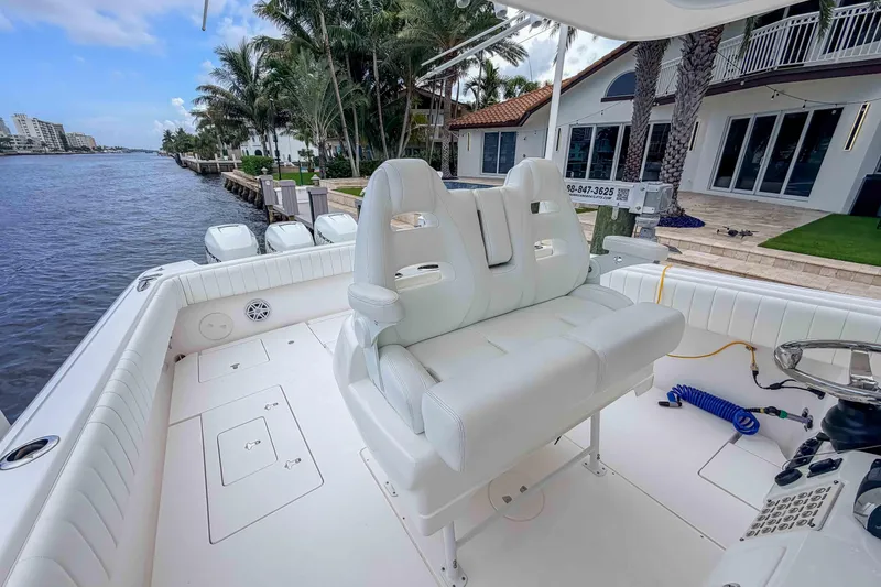Slide: The Image of 2019 Intrepid 400 Center Console boat with white seating, docked by waterfront homes. - 28