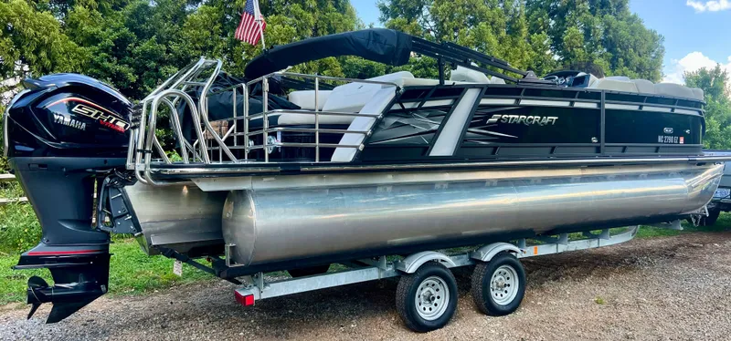 Slide: The Image of A 2022 Starcraft pontoon boat on a trailer, featuring an outboard motor and an American flag. - 1