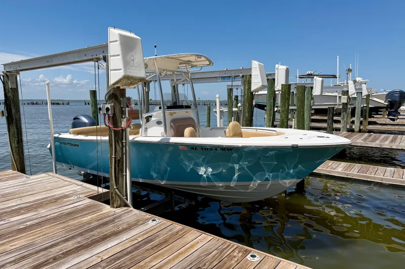 The Image of 2016 Sportsman Heritage 211 Center Console boat docked at marina under clear blue sky. - 1