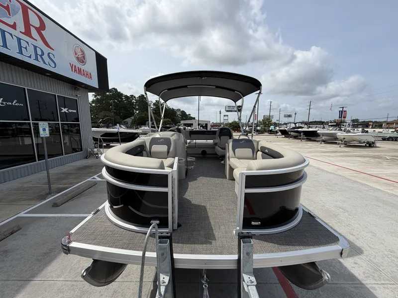 Slide: The Image of A 2024 Barletta A20UC pontoon boat is parked. It features a canopy and comfortable seating. - 5