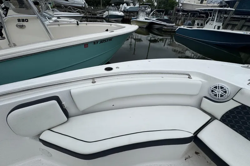 Slide: The Image of 2022 Tidewater 232 SS boat interior with white seating, docked among other boats. - 12