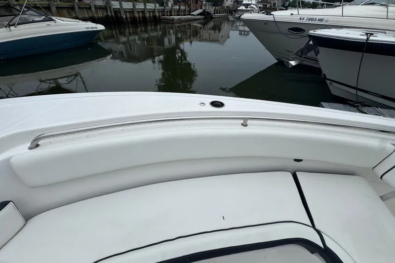 Slide: The Image of 2022 Tidewater 232 SS boat interior with white seating, docked near other boats. - 14