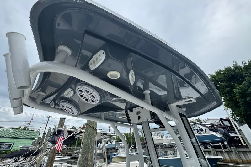 Slide: The Image of 2022 Tidewater 232 SS boat with T-top, speakers, and rod holders in marina setting. - 18
