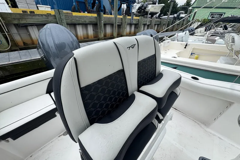 Slide: The Image of 2022 Tidewater 232 SS boat with dual cushioned seats at a marina. - 7