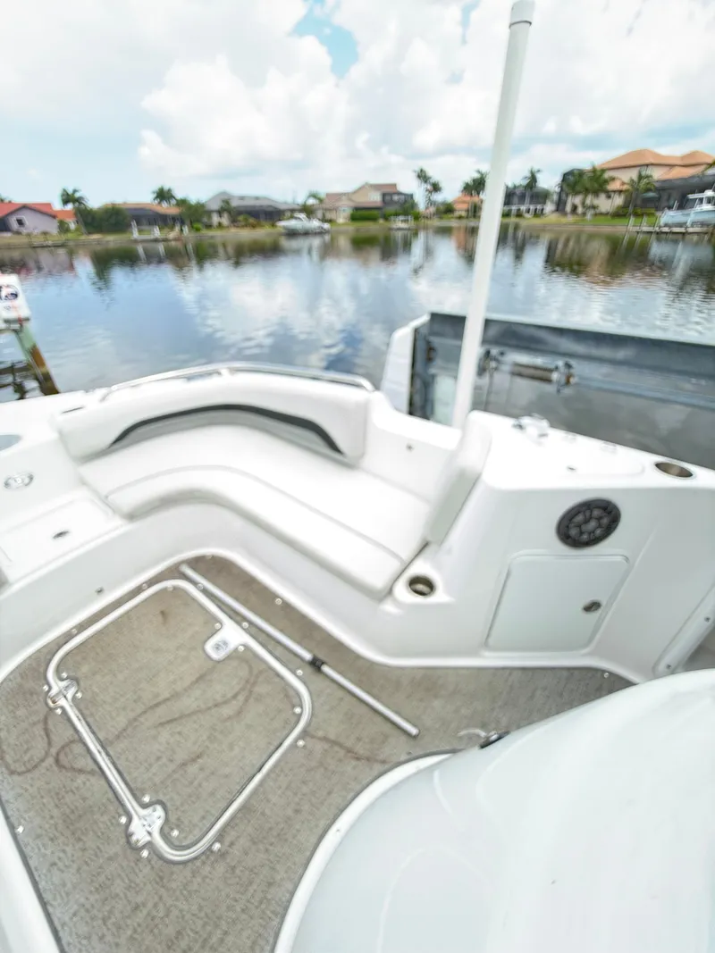 Slide: The Image of The image shows the rear of a Hurricane 231 SS boat with white seating and a lake in the background. - 14