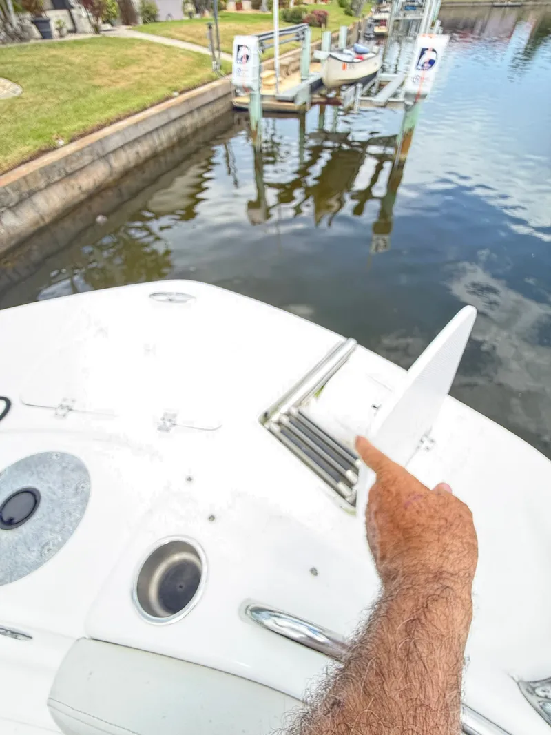 Slide: The Image of A man points at the deck of a Hurricane 231 SS boat docked in a calm area. - 17