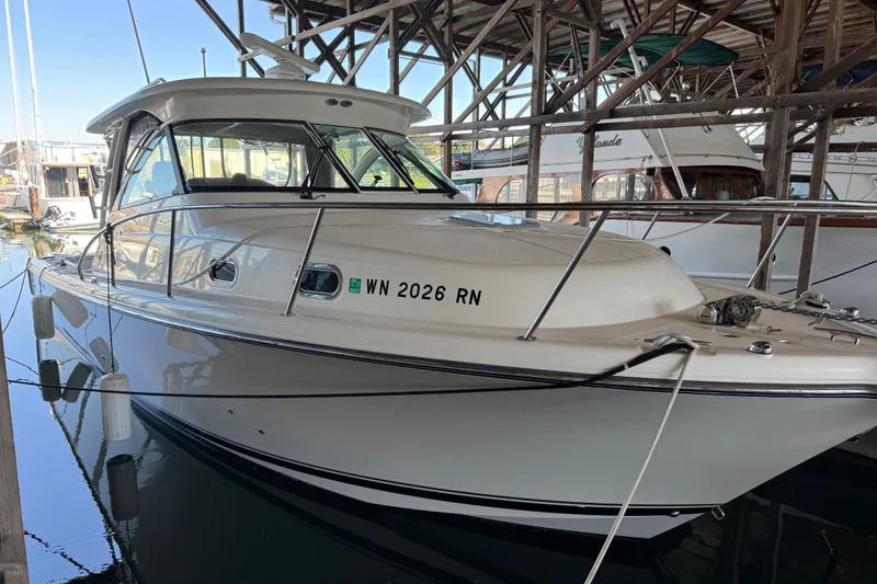 The Image of 2010 Pursuit OS 345 Offshore boat docked in a marina under shelter. - 0