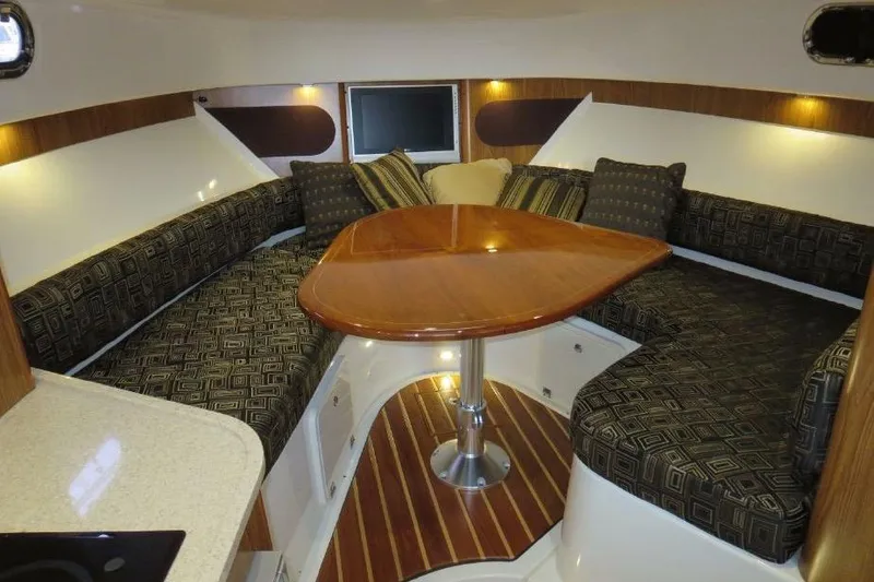 Slide: The Image of 2010 Pursuit OS 345 Offshore cabin interior with cushioned seating and wooden table. - 13
