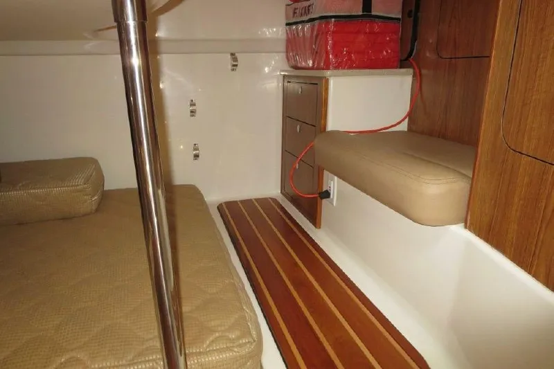 Slide: The Image of 2010 Pursuit OS 345 Offshore cabin interior with cushioned seating and wooden accents. - 14