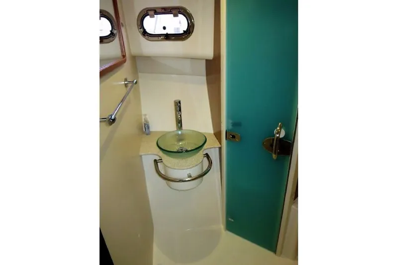 Slide: The Image of Bathroom interior of 2010 Pursuit OS 345 Offshore boat with glass sink and teal door. - 18