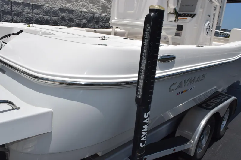 Slide: The Image of 2022 Caymas 26 HB boat, sleek white design, parked on a trailer. - 27