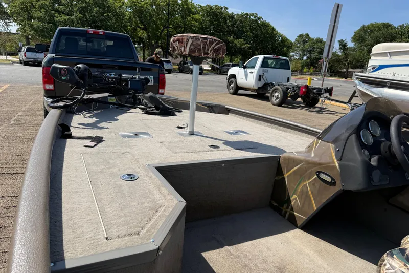 Slide: The Image of 2010 SeaArk Stealth 190 boat on trailer, parked near pickup trucks in a sunny lot. - 24