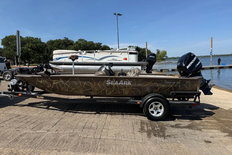 Slide: The Image of 2010 SeaArk Stealth 190 boat on trailer by lake, featuring Mercury outboard motor. - 5