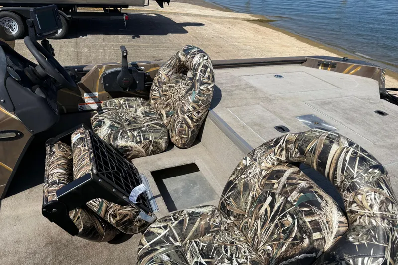 Slide: The Image of 2010 SeaArk Stealth 190 boat with camouflage seats, docked by the water. - 23