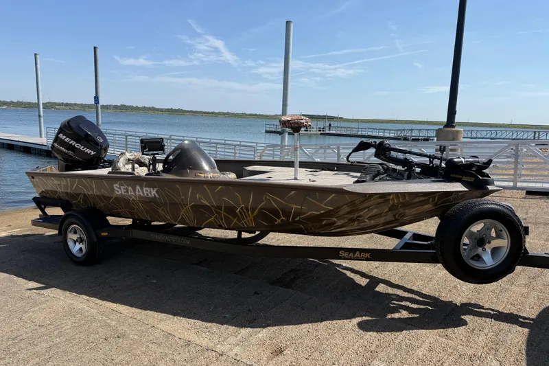 Slide: The Image of 2010 SeaArk Stealth 190 boat on trailer by the waterfront, featuring a Mercury outboard motor. - 15