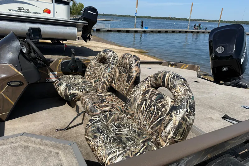 Slide: The Image of 2010 SeaArk Stealth 190 boat with camouflage seats docked by a lake. - 22
