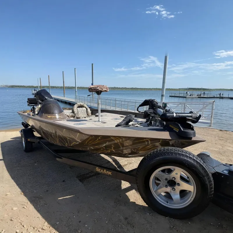 The Image of 2010 SeaArk Stealth 190 boat on trailer by a lakeside dock. - 0