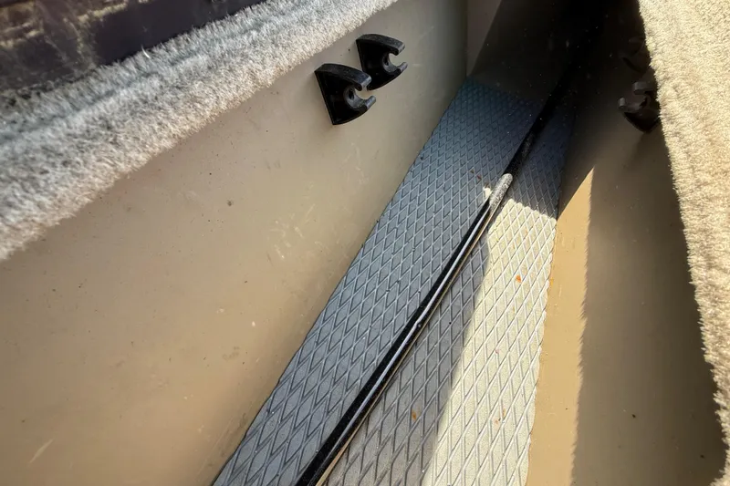 Slide: The Image of Interior view of a 2010 SeaArk Stealth 190 boat, featuring carpeted surfaces and rod storage. - 30