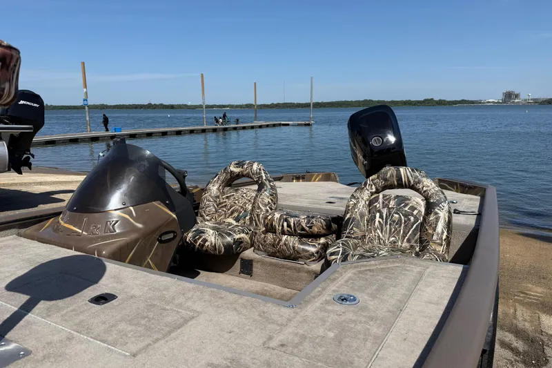 Slide: The Image of 2010 SeaArk Stealth 190 boat with camouflage seats docked by a serene lake. - 21