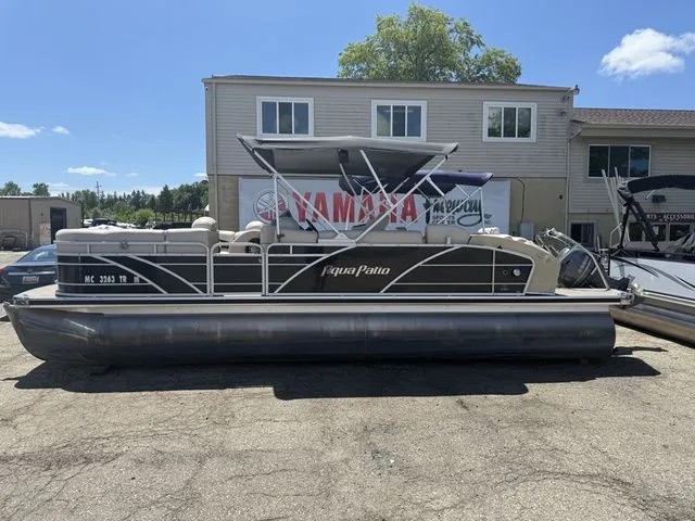 The Image of A 2014 Godfrey AP 240 pontoon boat is parked on a lot in front of a building. - 1