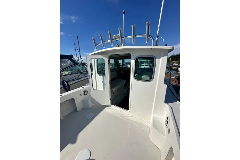 Slide: The Image of 2022 Parker 2120 Sport Cabin boat with open cabin door, docked under clear blue sky. - 13