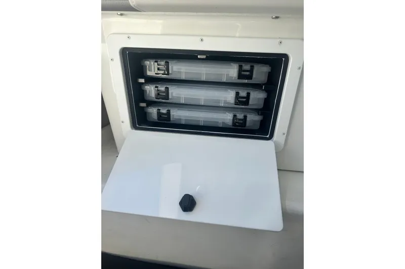 Slide: The Image of Storage compartment with three tackle boxes in a 2022 Parker 2120 Sport Cabin boat. - 19