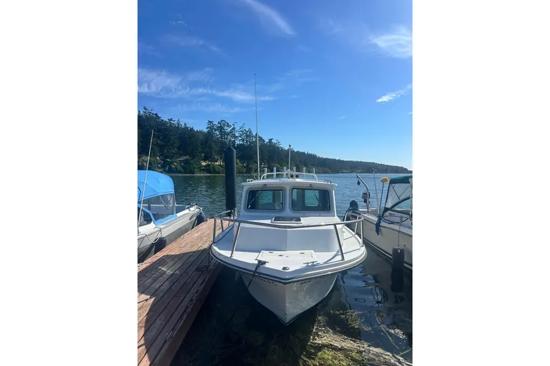 Slide: The Image of 2022 Parker 2120 Sport Cabin boat docked on a sunny day by the lake. - 2