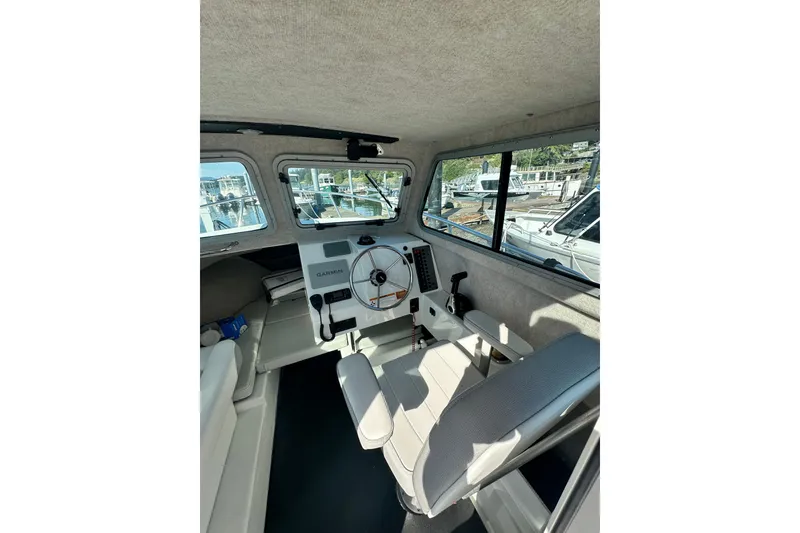 Slide: The Image of Interior of a 2022 Parker 2120 Sport Cabin boat with steering wheel and seating. - 22