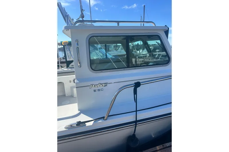 Slide: The Image of 2022 Parker 2120 Sport Cabin boat docked, showcasing sleek design and window details. - 3
