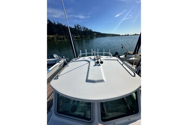 Slide: The Image of 2022 Parker 2120 Sport Cabin boat docked on a serene lake under a clear blue sky. - 7
