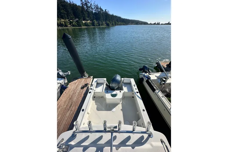 Slide: The Image of 2022 Parker 2120 Sport Cabin boat docked on a serene lake with wooded shoreline. - 8