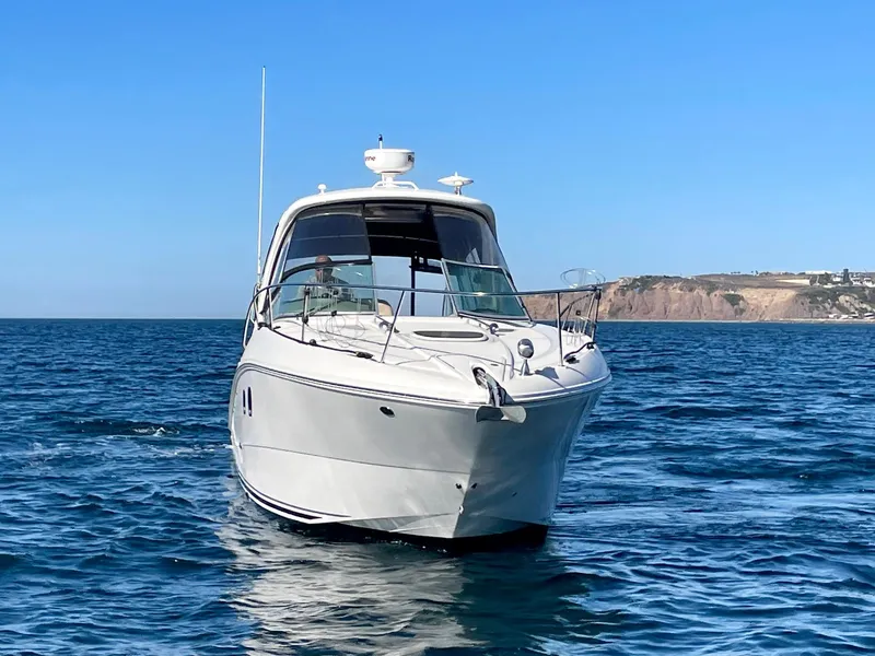 Slide: The Image of 2014 Sea Ray 330 Sundancer cruising on open water with coastal cliffs in the background. - 4