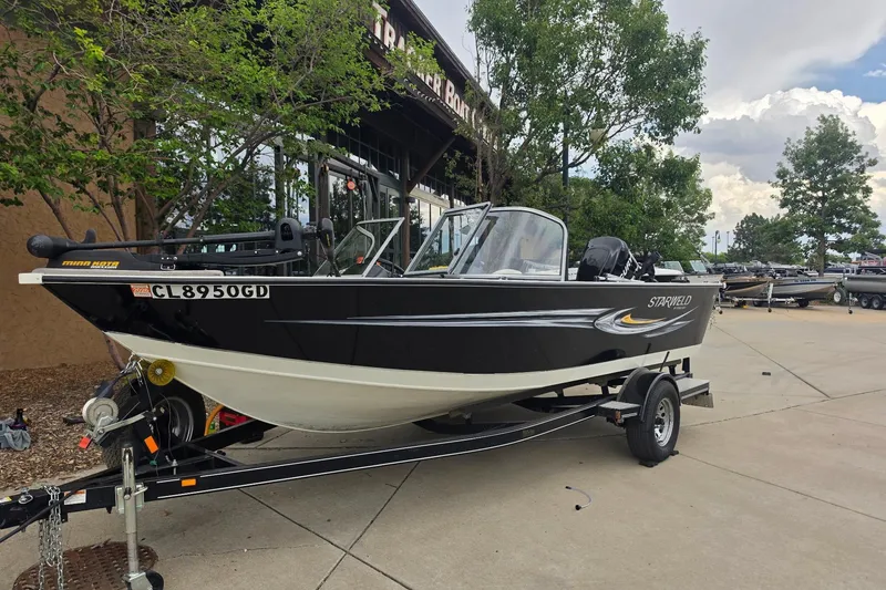 The Image of 2010 Starcraft NexStar 1910 I/O boat on trailer, parked outdoors near trees. - 0