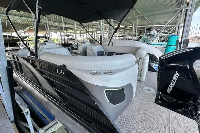Slide: The Image of 2021 Bennington L Bowrider 25 Quad Bench pontoon boat docked under cover. - 3