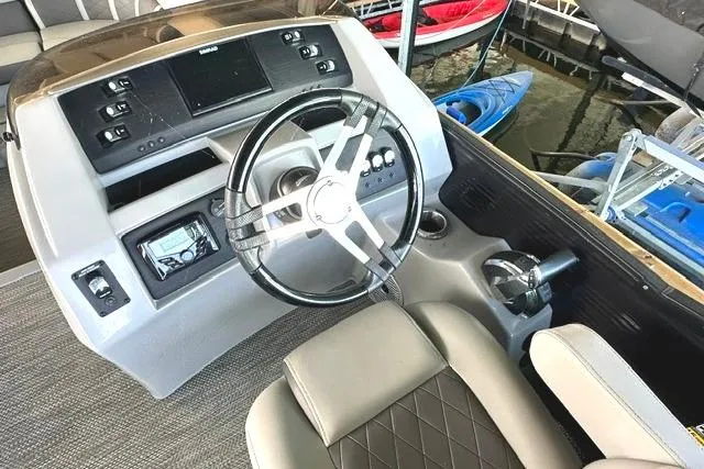 Slide: The Image of 2021 Bennington L Bowrider 25 Quad Bench dashboard with steering wheel and control panel. - 8