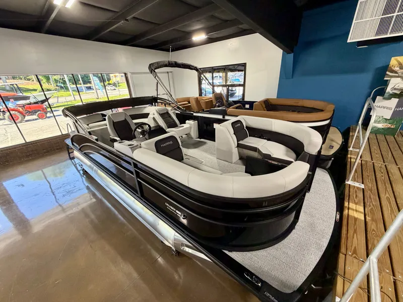 Slide: The Image of A sleek pontoon boat with gray seating and black railing is displayed in a showroom. - 3