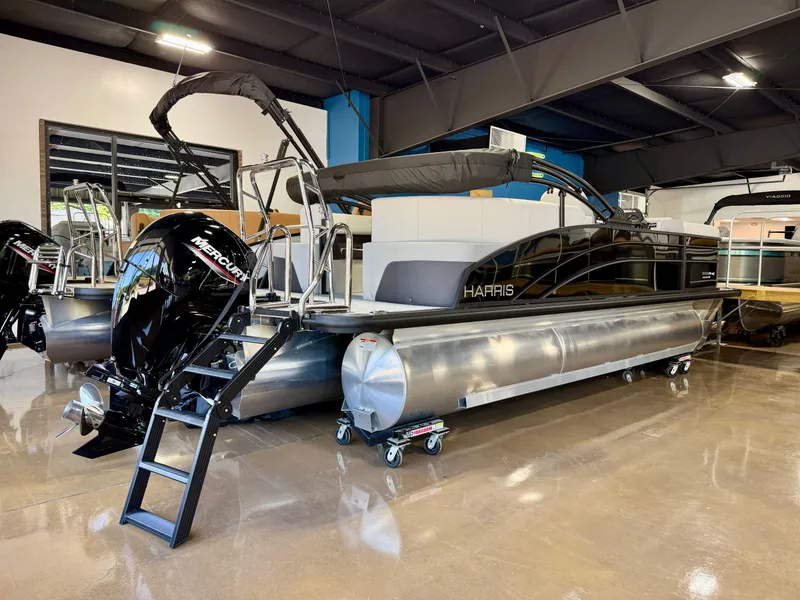 Slide: The Image of A Harris Cruiser 210 Heritage pontoon boat is in a showroom. It features a Mercury outboard motor. - 4