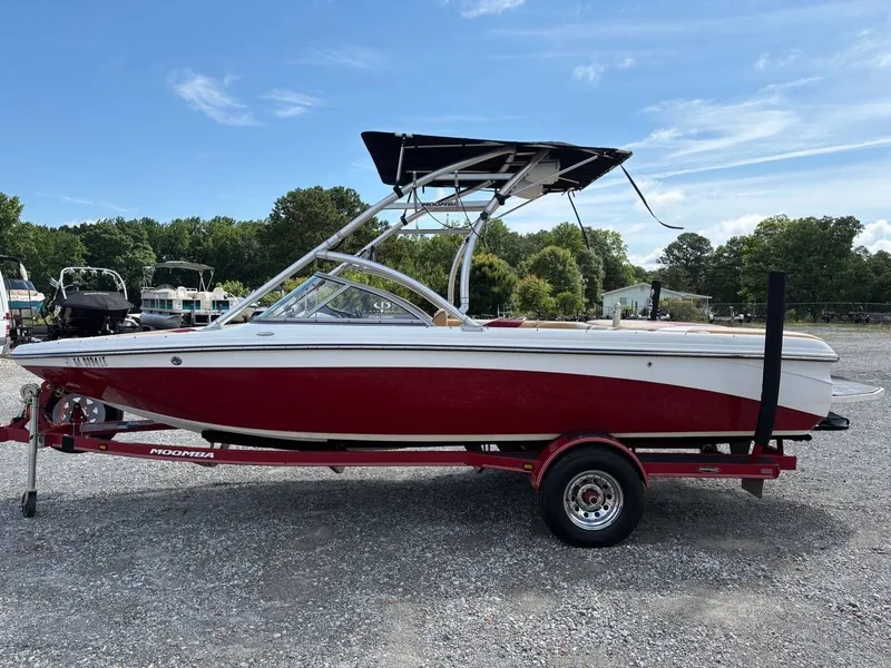 The Image of A red 2006 Moomba Mobius LSV boat on a trailer in a gravel lot. - 1