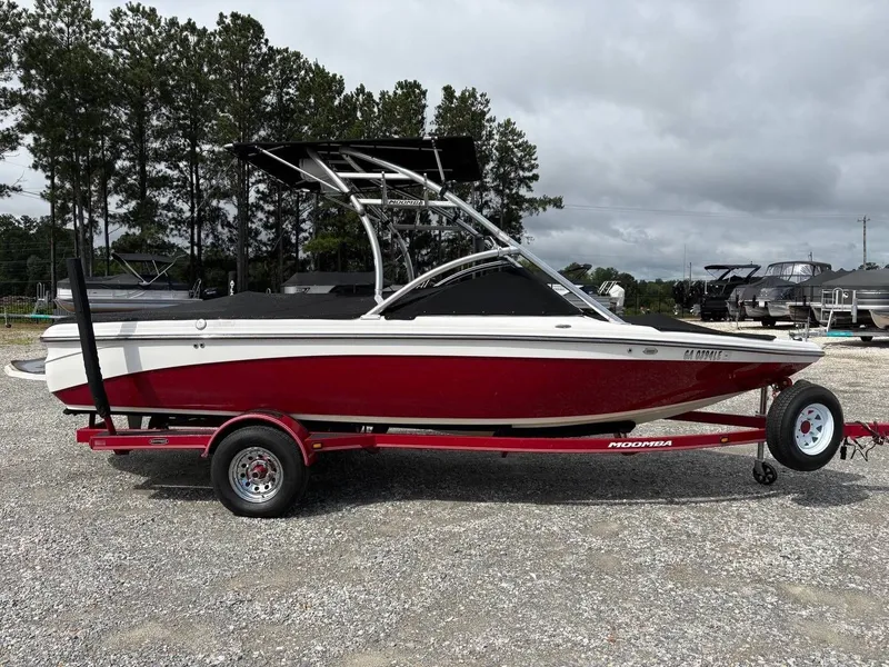 Slide: The Image of A red 2006 Moomba Mobius LSV boat on a trailer in a gravel lot. - 2