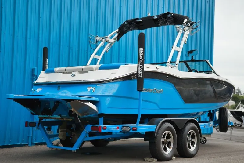 Slide: The Image of A blue and black 2016 MasterCraft NXT20 boat on a trailer in front of a blue wall. - 4