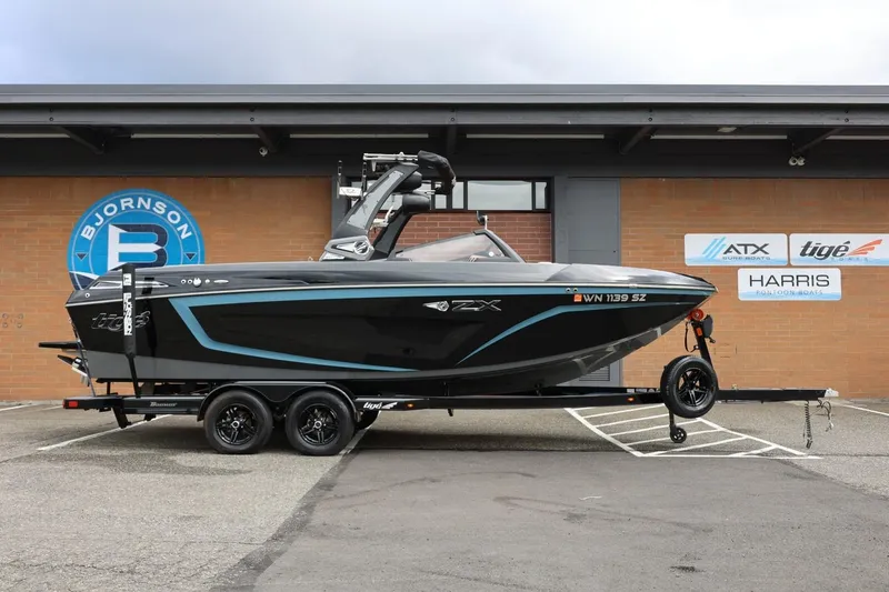 Slide: The Image of 2021 Tigé 23ZX boat on trailer, parked outside Bjornson building. - 2