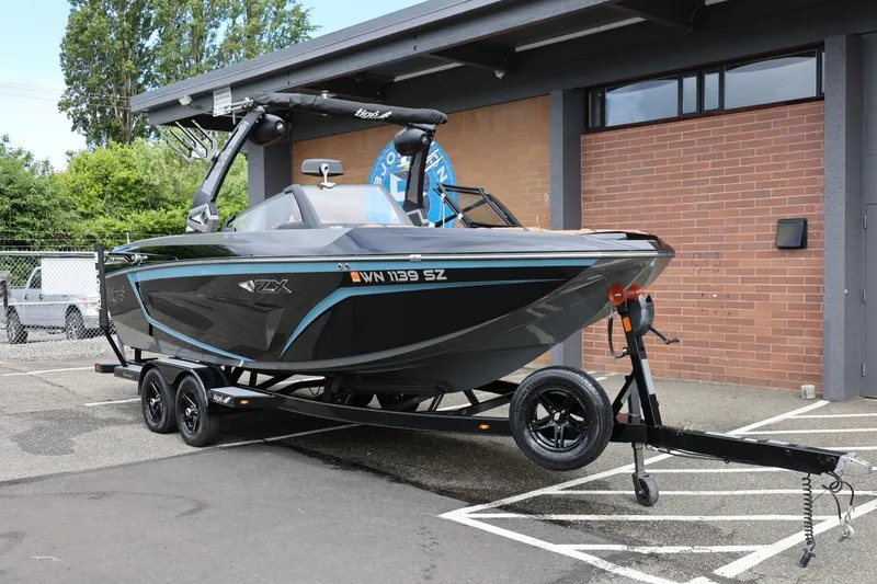 Slide: The Image of 2021 Tigé 23ZX boat on trailer, parked near a brick building. - 3