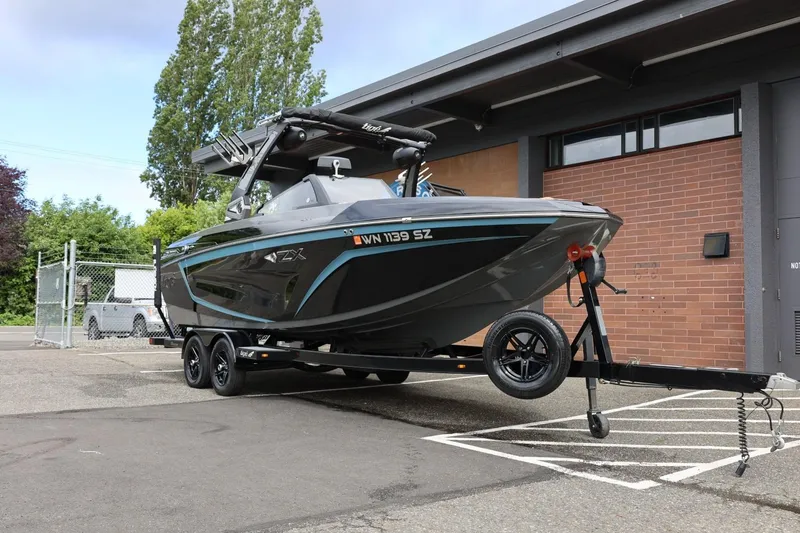 Slide: The Image of 2021 Tigé 23ZX boat on trailer, parked near a brick building. - 4