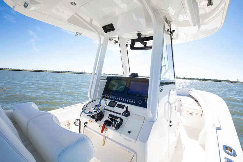Slide: The Image of 2022 Regulator 28 Forward Seating boat interior with helm, on a sunny day at sea. - 8