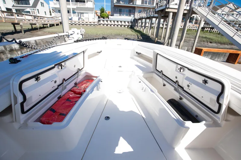 Slide: The Image of 2022 Regulator 28 Forward Seating boat with open storage compartments, docked near waterfront homes. - 14