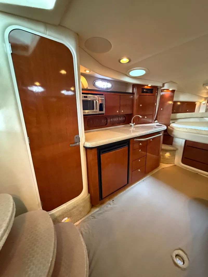 Slide: The Image of The 2007 Sea Ray 340 Sundancer interior cabin features an elegant galley with wooden cabinetry. - 24