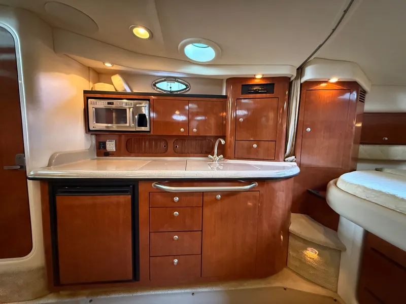 Slide: The Image of The interior of a 2007 Sea Ray 340 Sundancer features a well-equipped galley with wooden cabinetry. - 23
