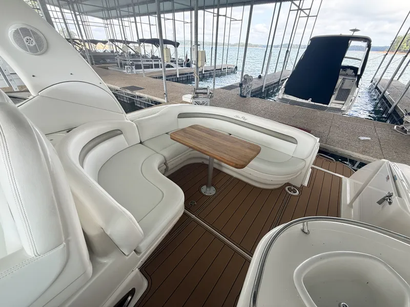 Slide: The Image of The 2007 Sea Ray 340 Sundancer features an elegant seating area with a wooden table at a dock. - 14
