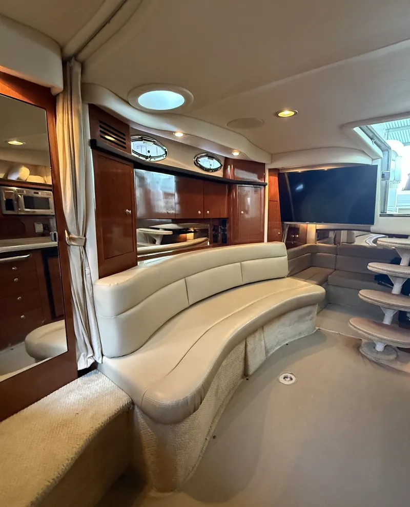 Slide: The Image of Interior of a 2007 Sea Ray 340 Sundancer with curved leather seating and wooden cabinetry. - 26